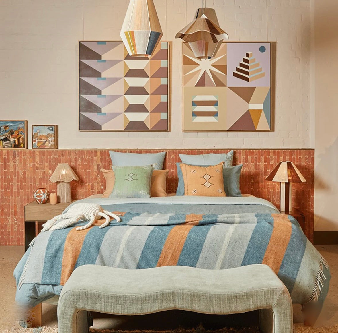 Bedroom with a bed featuring striped bedding, decorative bedside lamps, pillows, and geometric wall art.