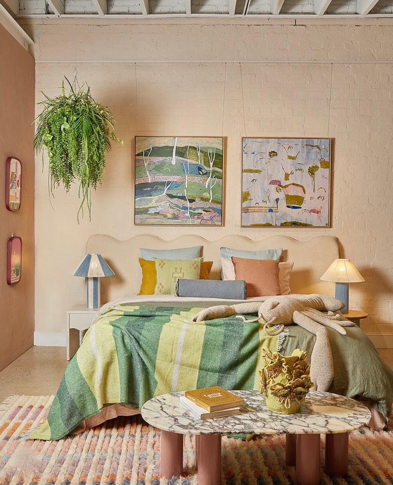 Bedroom with a bed featuring striped bedding, decorative bedside lamps, pillows, and abstract wall art.