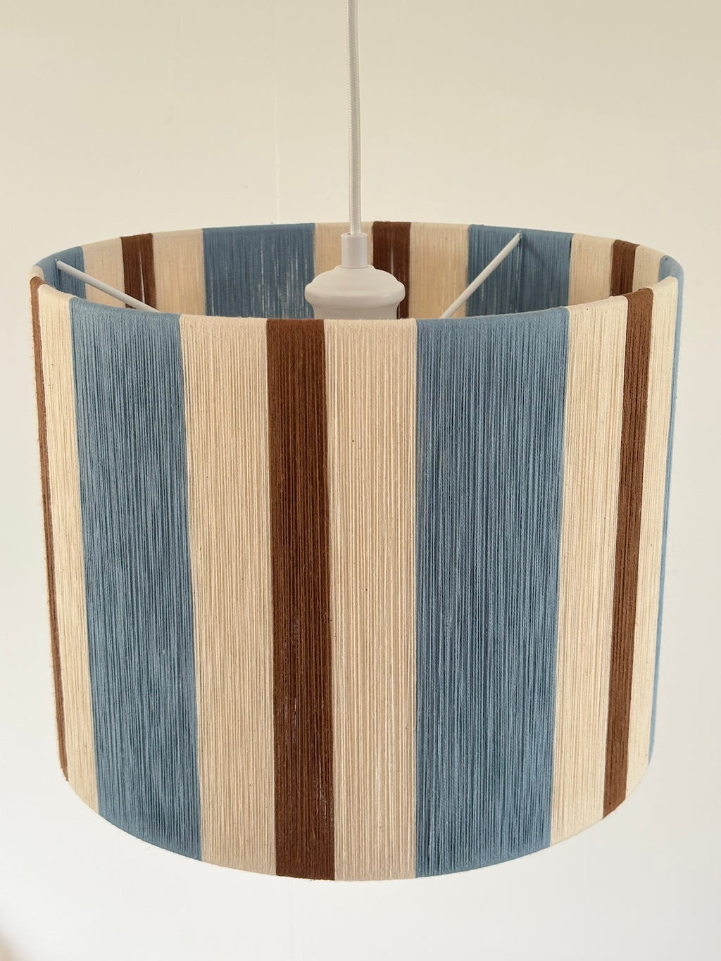 Top view of the Cléo Drum Small pendant light, showing handwoven vertical stripes in cloud blue, natural and fawn yarn