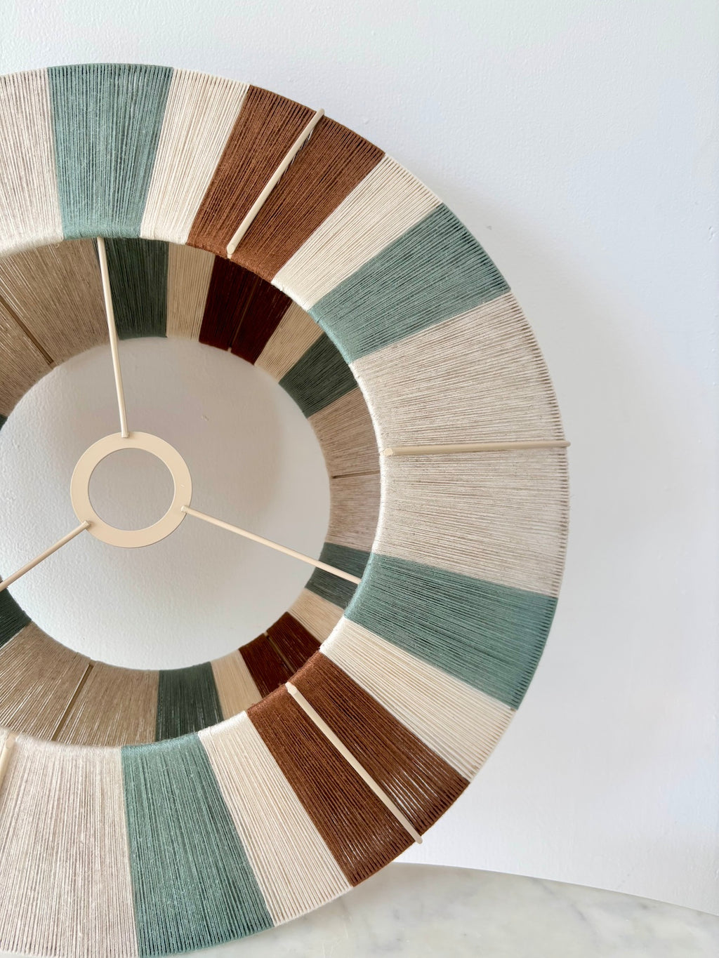 Close-up of a Sarto Orb section showing handwoven yarn in sage, natural and fawn on the round ufo shaped frame