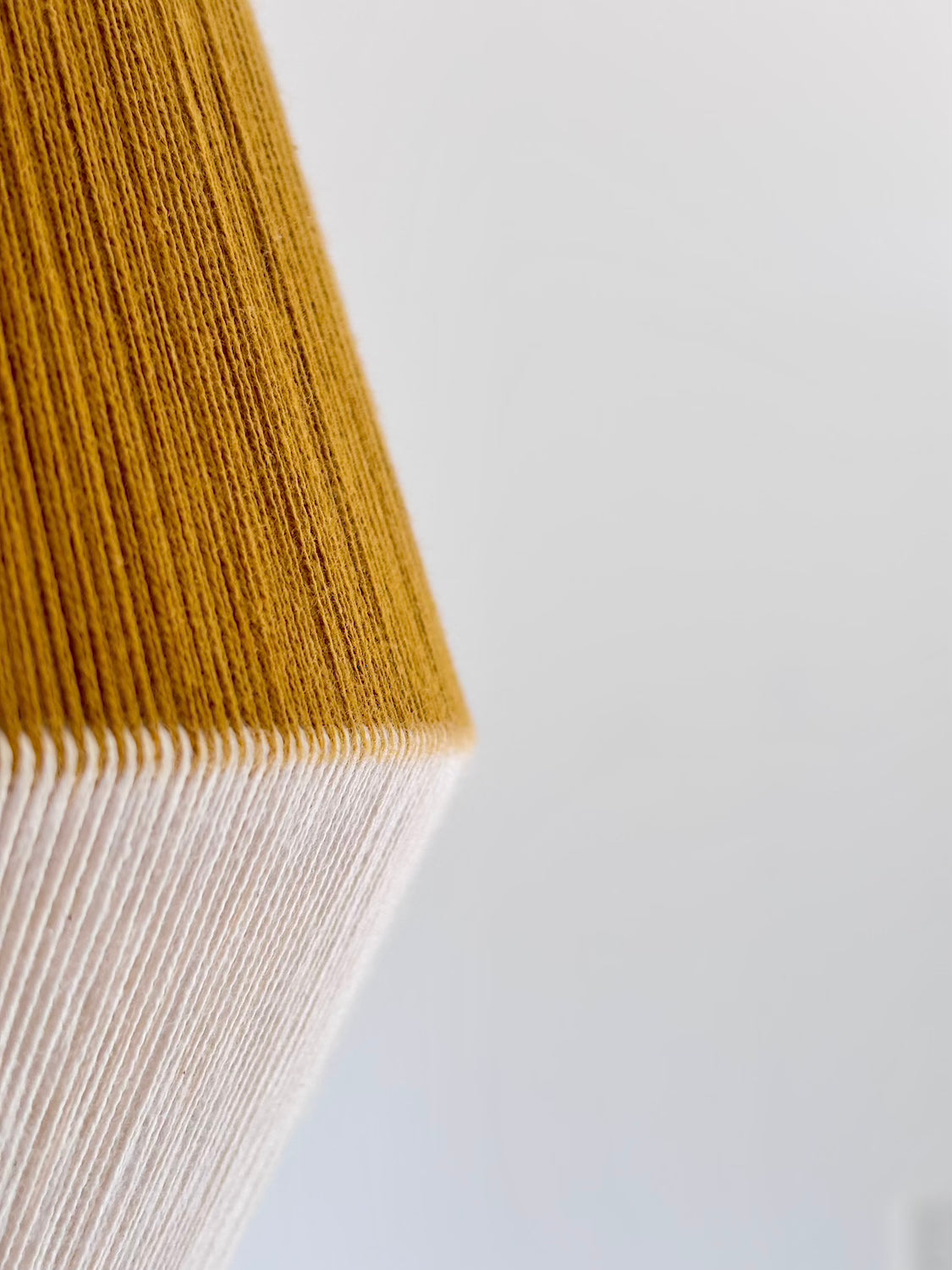 Closeup side viewhandwoven Baya pendant light in mustard and natural colours by Skye Lightly.