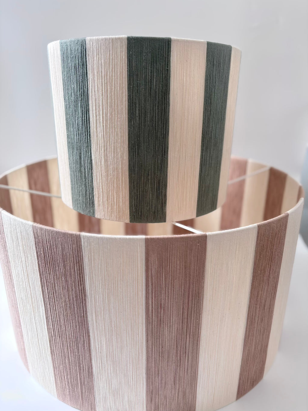 Handwoven small and large drum pendant light with beige and sage horizontal stripes, designed by Skye Lightly.
