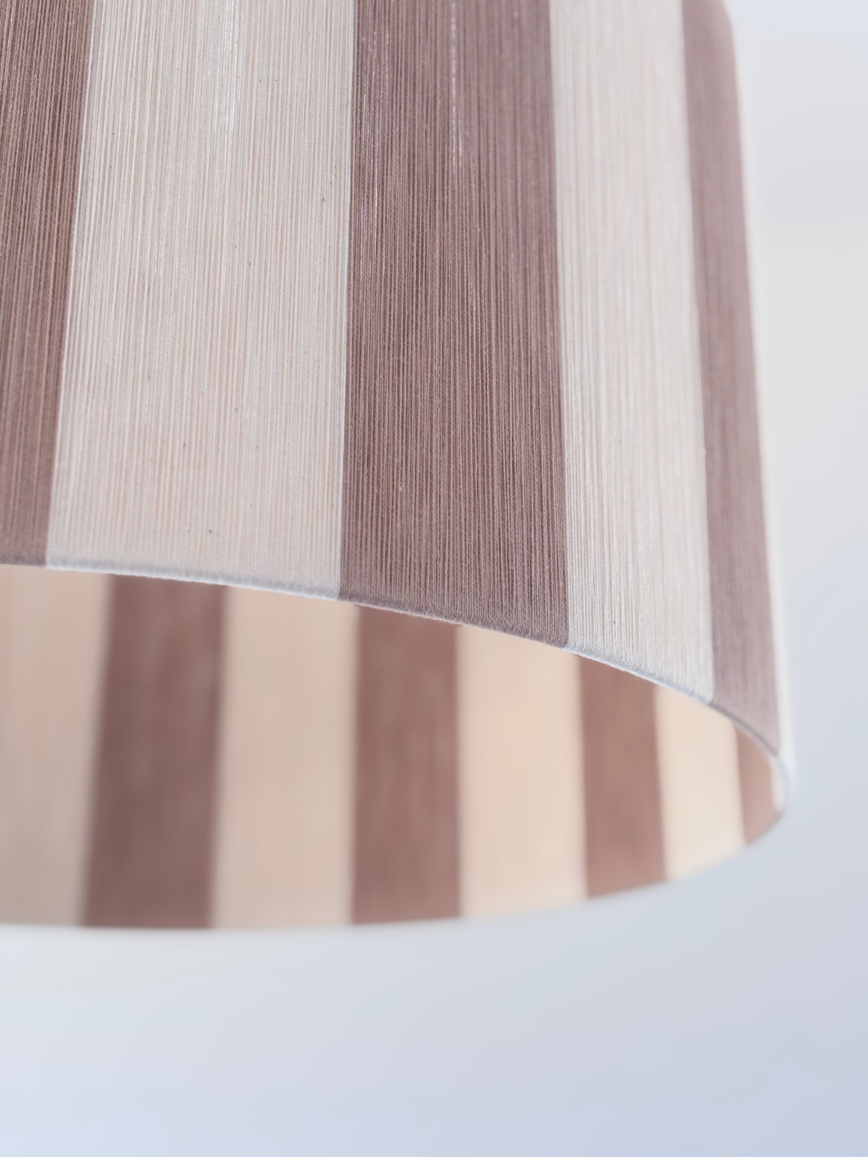 Closeup shot of handwoven drum pendant light with beige and natural stripes by Skye Lightly.