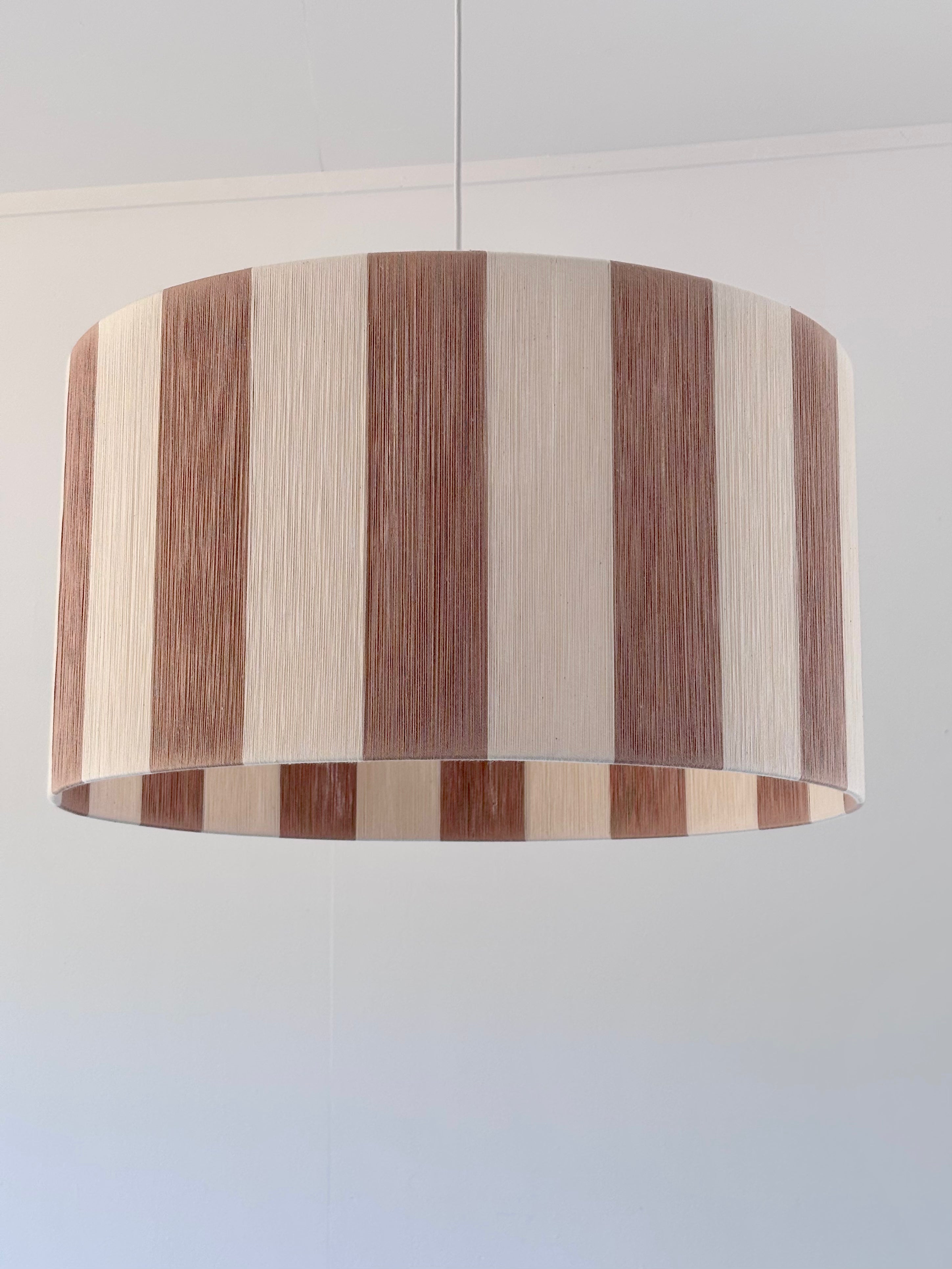 Handwoven drum pendant light with beige and natural stripes by Skye Lightly.