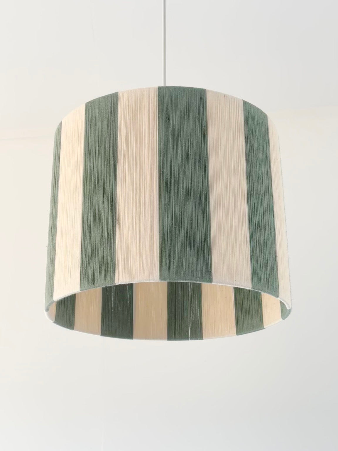 bottom view of handwoven drum pendant light with sage and natural stripes by Skye Lightly.