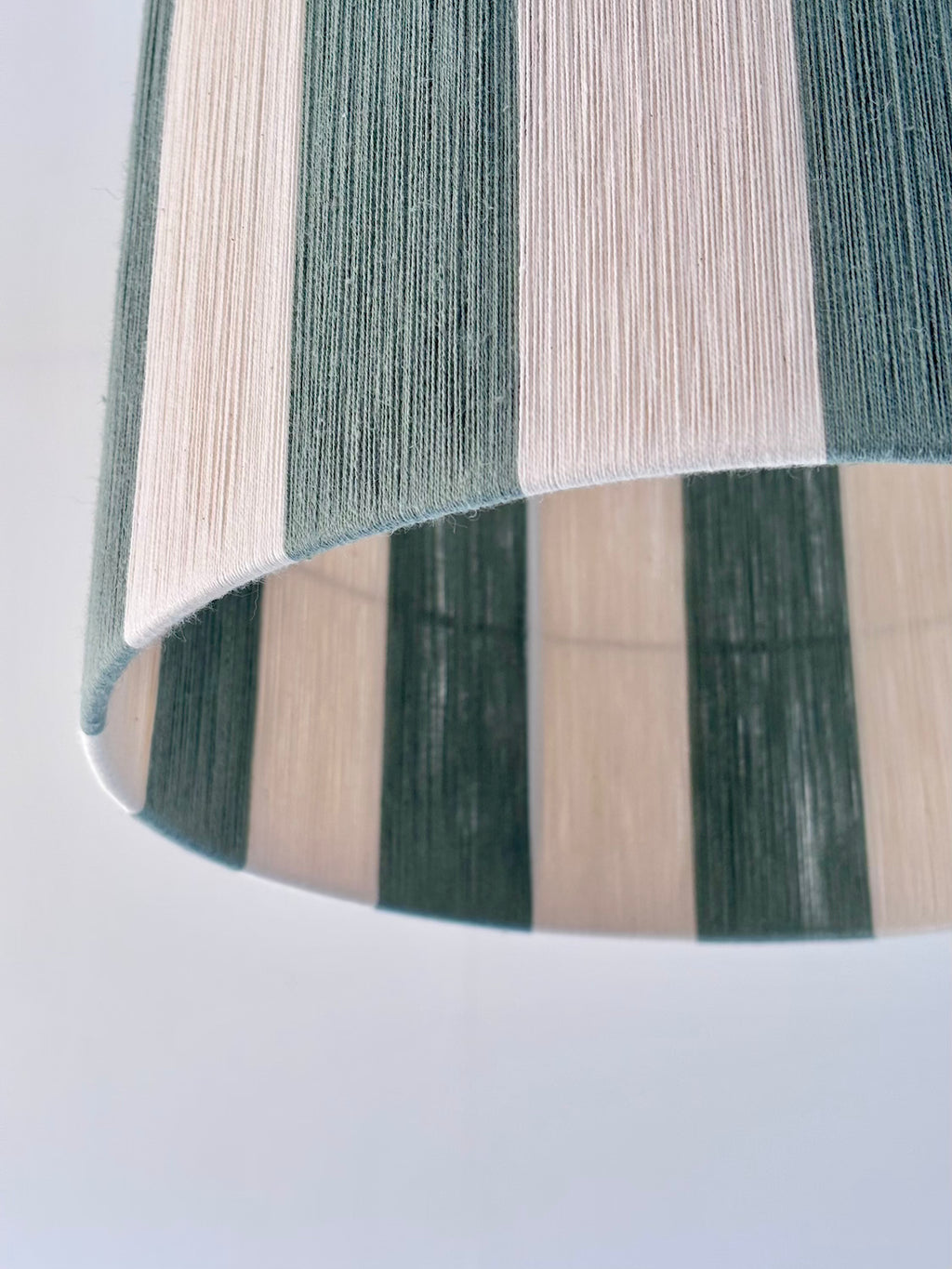 closeup of handwoven drum pendant light with sage and natural stripes by Skye Lightly.