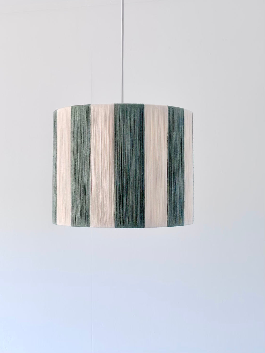 Handwoven drum pendant light with sage and natural stripes by Skye Lightly.