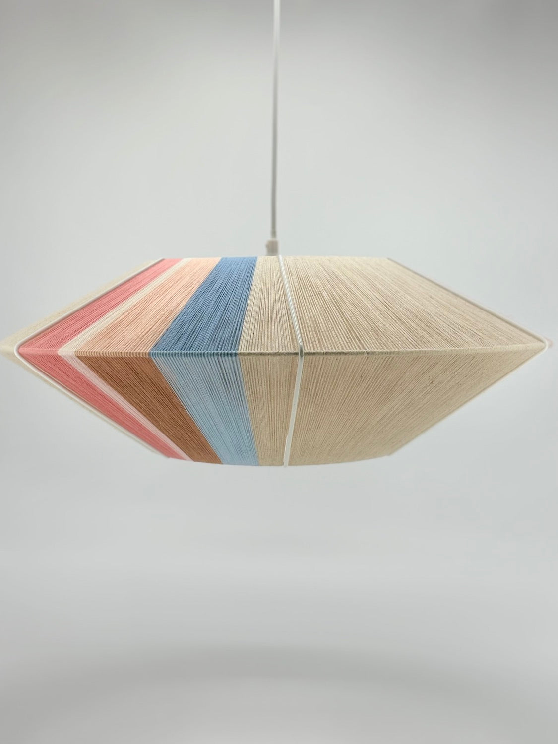 off center view of Jean Orb pendant light handwoven in cinnamon, peach, chambray, salmon, pale rose and natural yarns by Skye Lightly