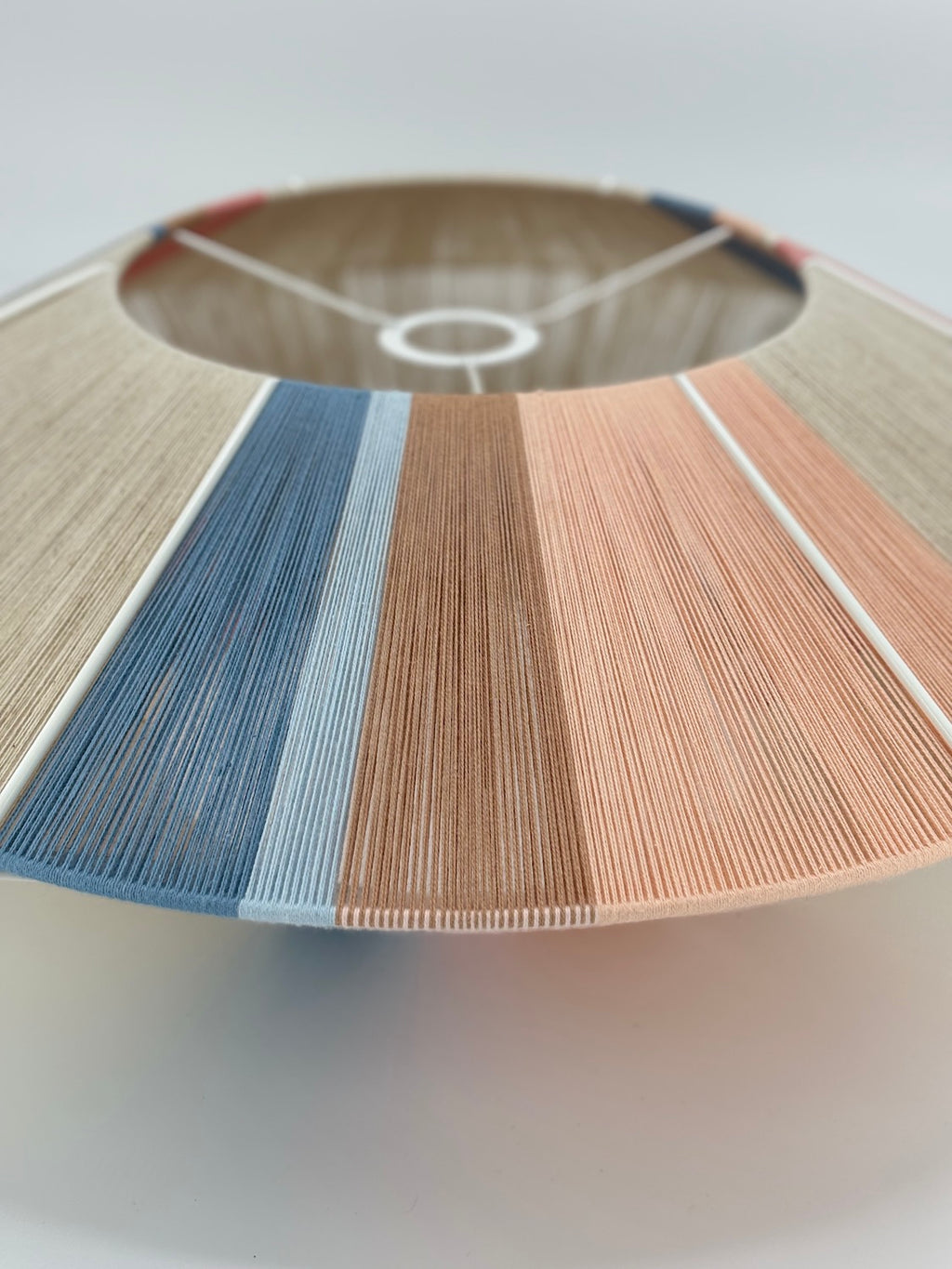 side view ofJean Orb pendant light handwoven in cinnamon, peach, chambray, salmon, pale rose and natural yarns by Skye Lightly