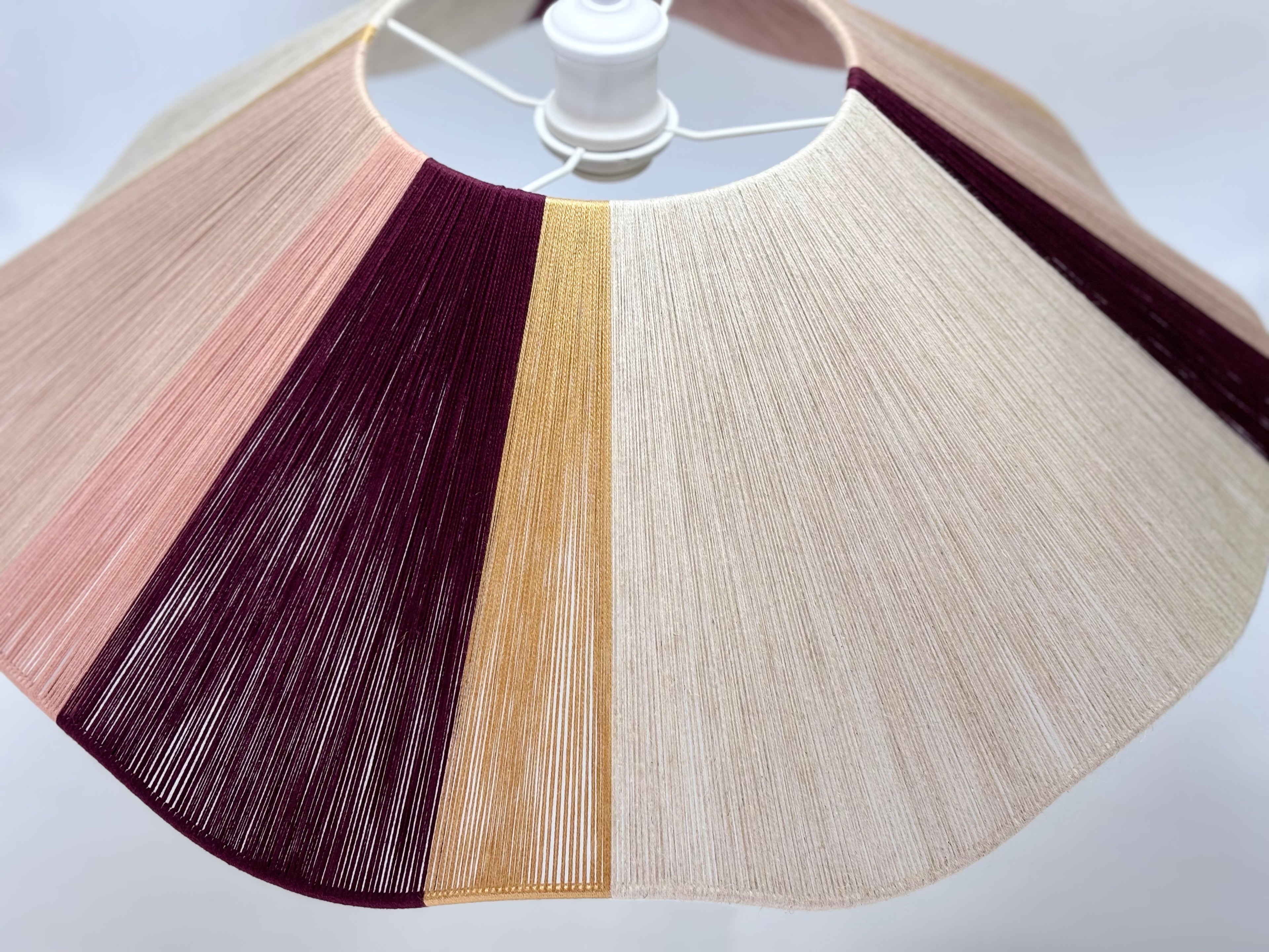 front view of handwoven cottesloe Wave pendant light in burgundy, blush, gold and natural yarns by Skye Lightly.