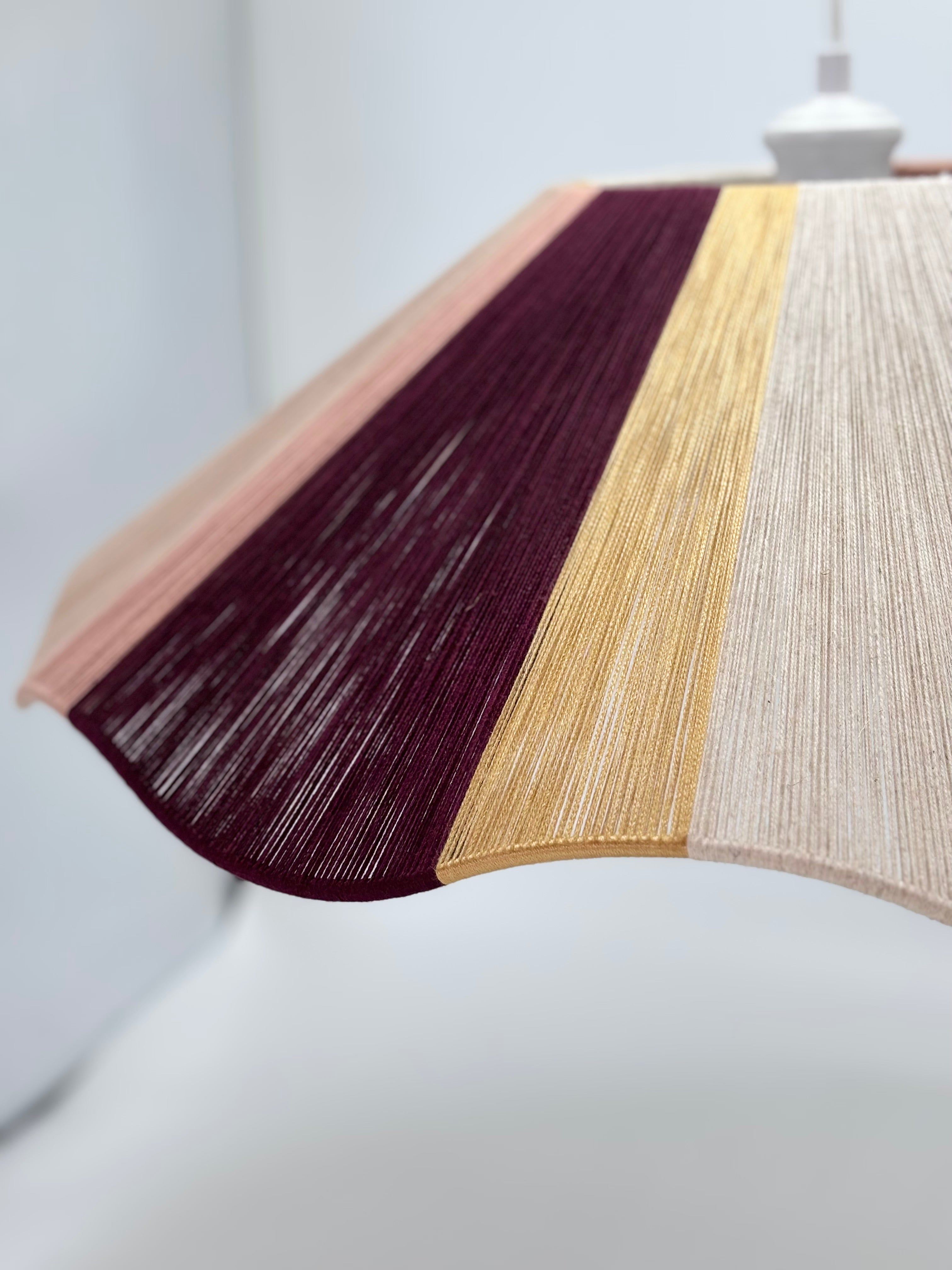 side view of handwoven cottesloe Wave pendant light in burgundy, blush, gold and natural yarns by Skye Lightly.