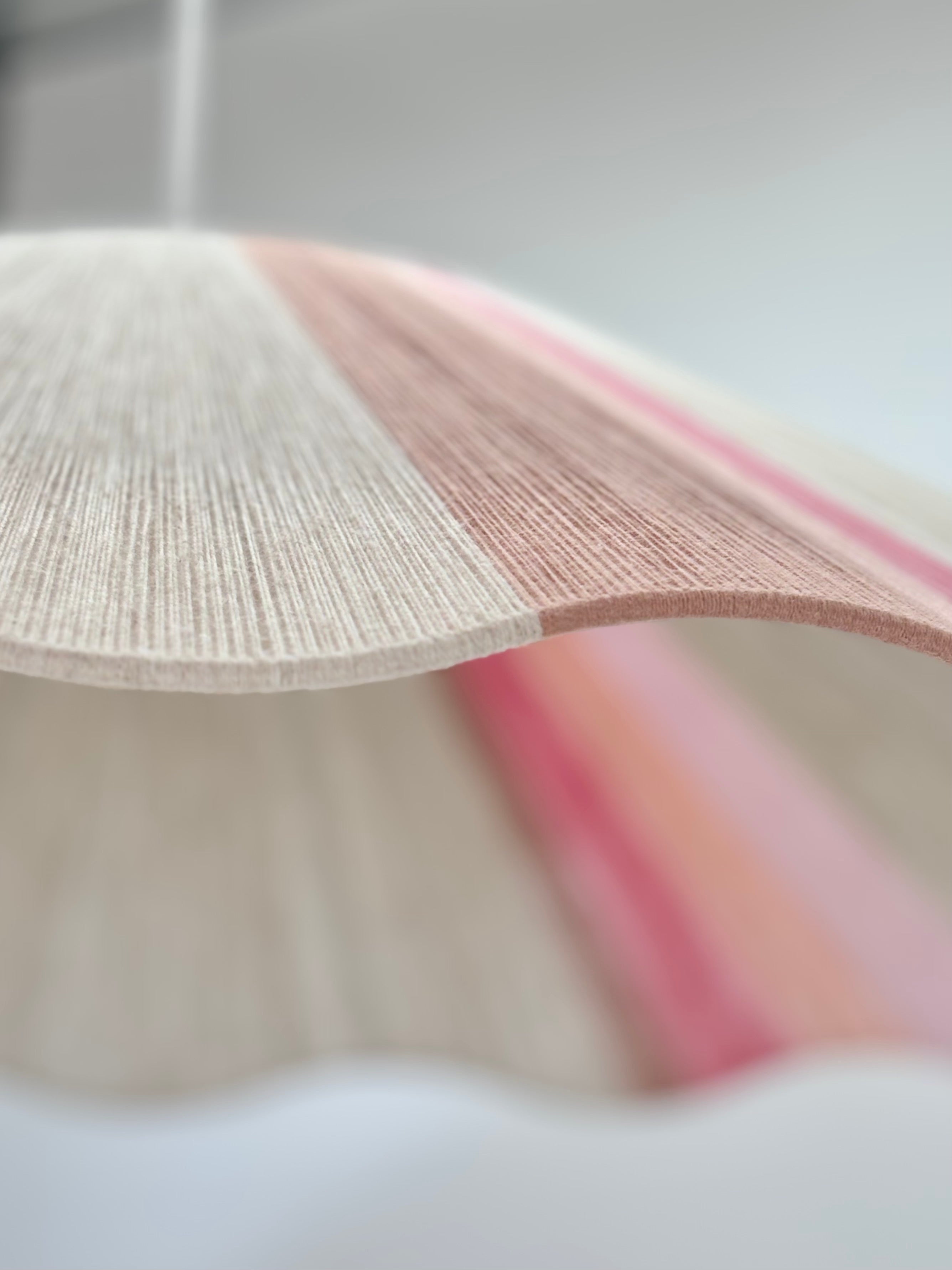 Portrait view of handwoven Knox wave pendant light in soft pink and natural tones by Skye Lightly.