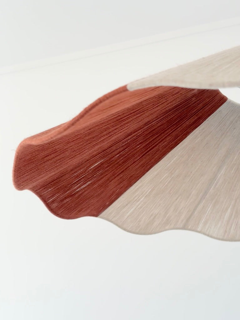 A pendant lamp close-up image with a natural linen and red color block yarn design, hanging against a white background.