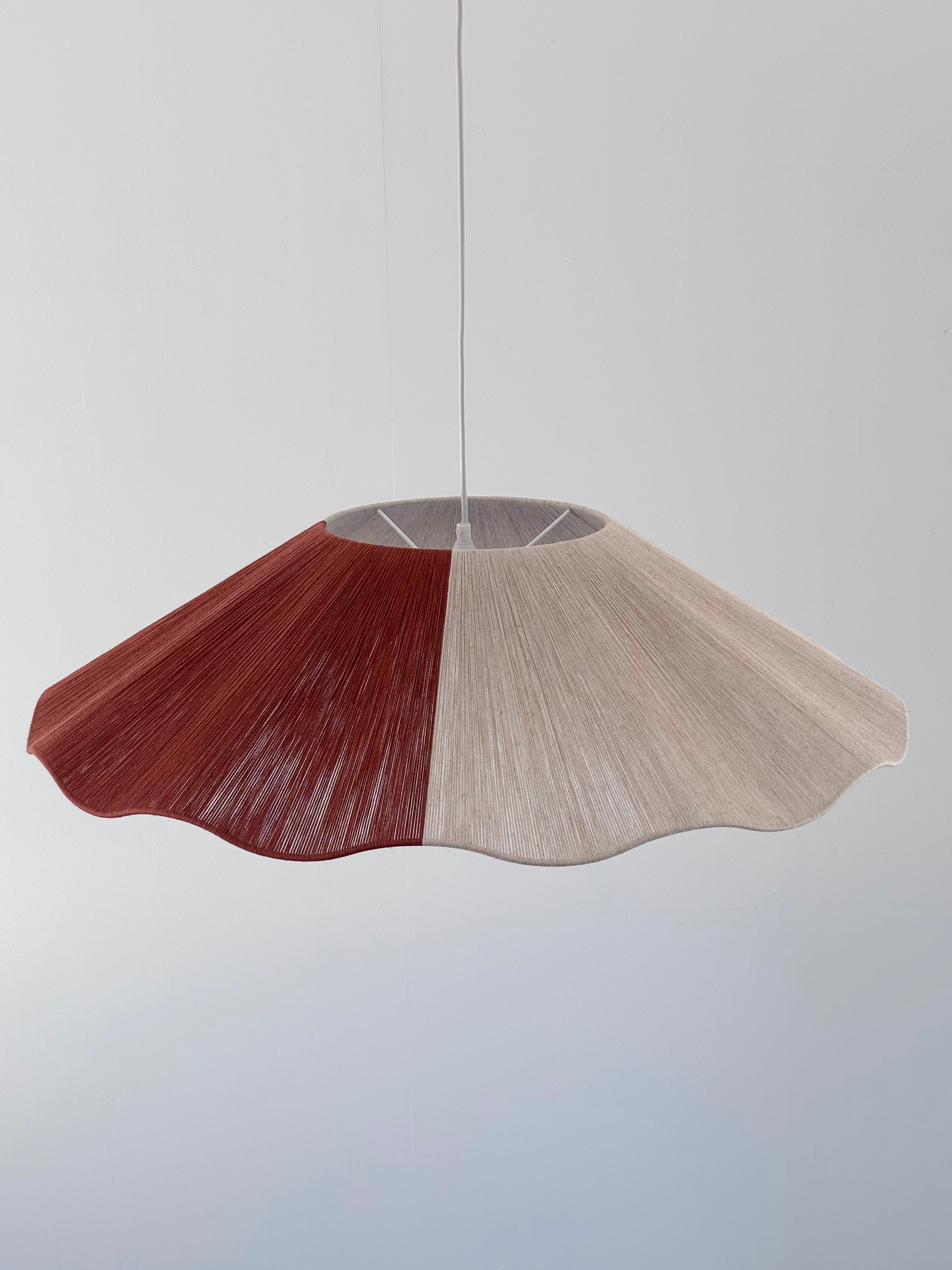 A top view image showing a pendant lamp with a natural linen and red color block yarn design, hanging against a white background.