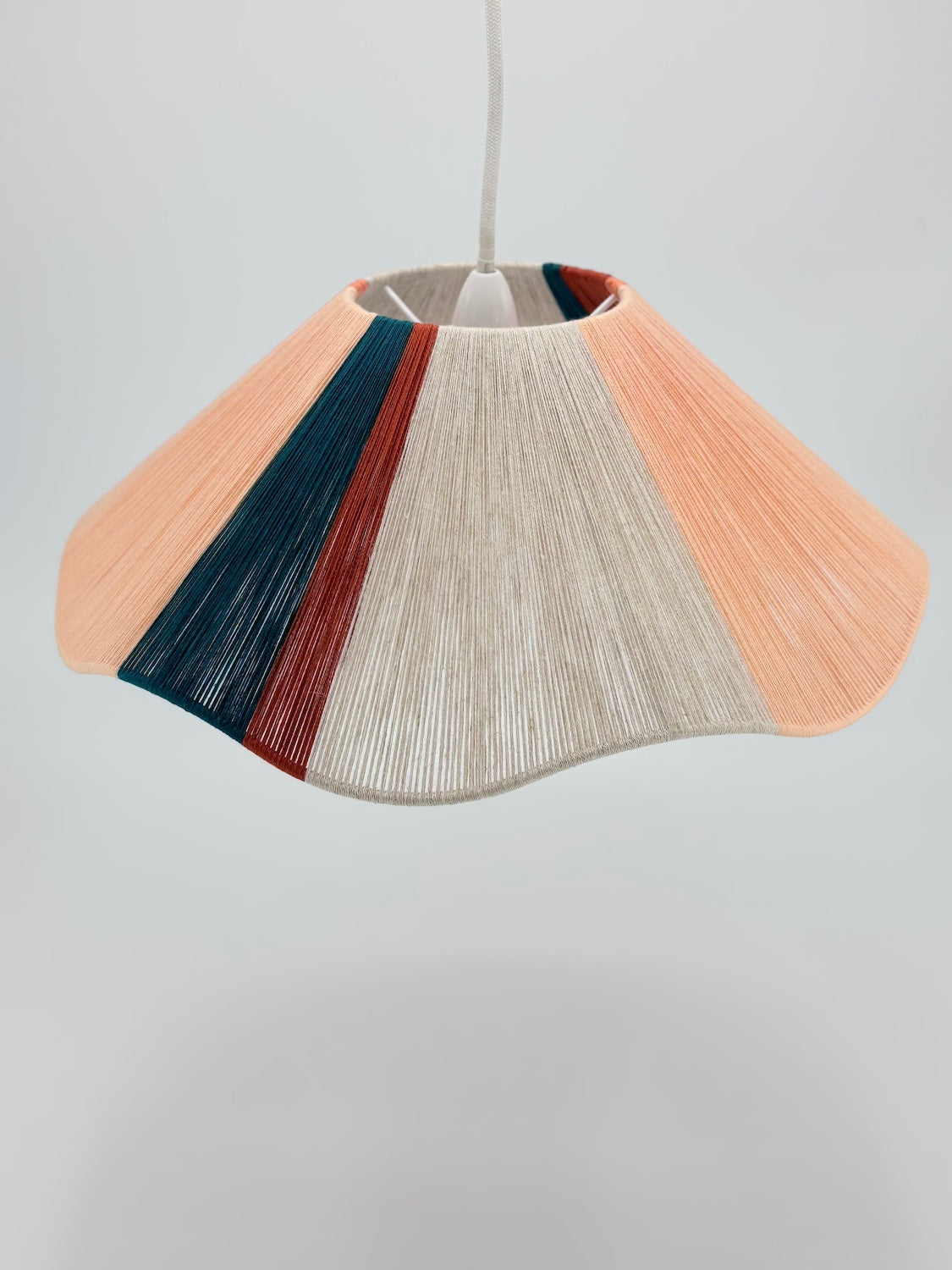 front view of venice Wave pendant light handwoven in peach, teal, burgundy and natural yarns by Skye Lightly.
