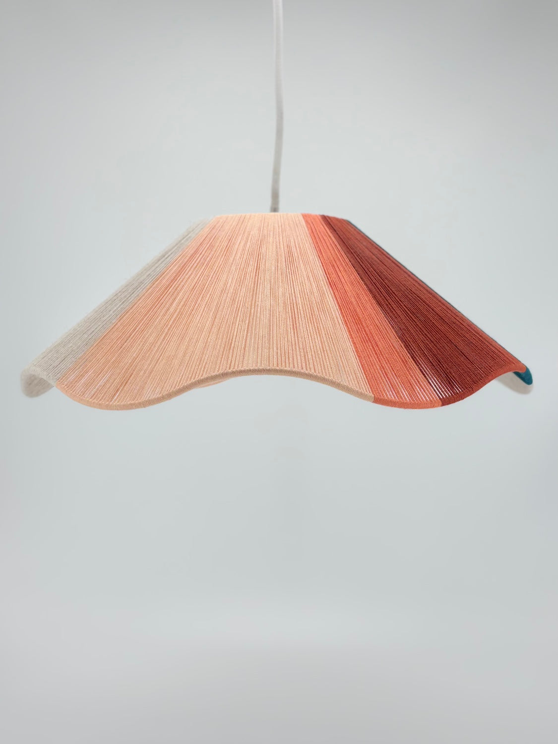 portrait view of venice Wave pendant light handwoven in peach, teal, burgundy and natural yarns by Skye Lightly.